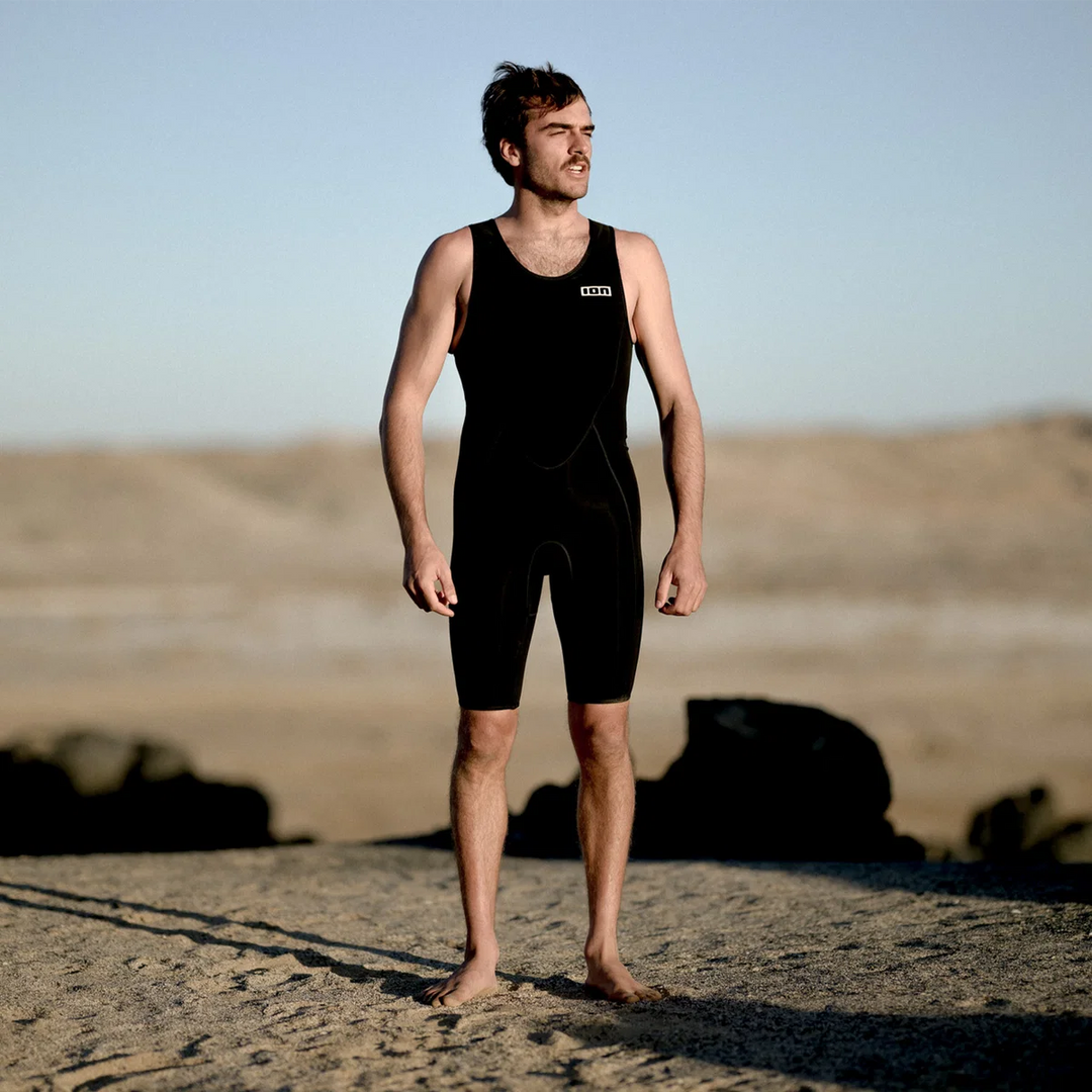 Man in ION Monoshorty 2.0 herenwetsuit zwart op het strand